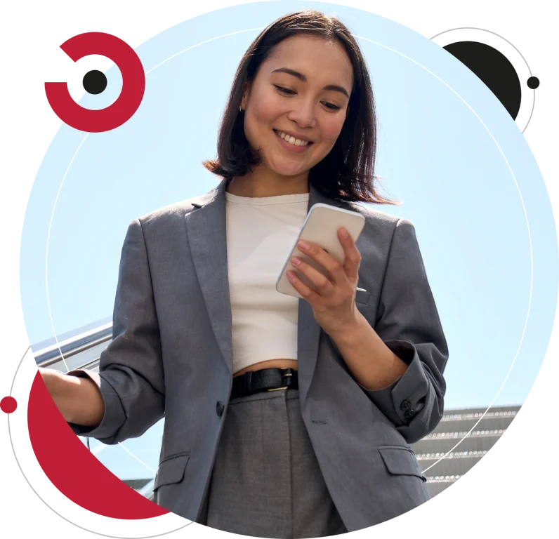 Smiling young Asian business woman wearing suit standing on urban escalator using her smartphone.