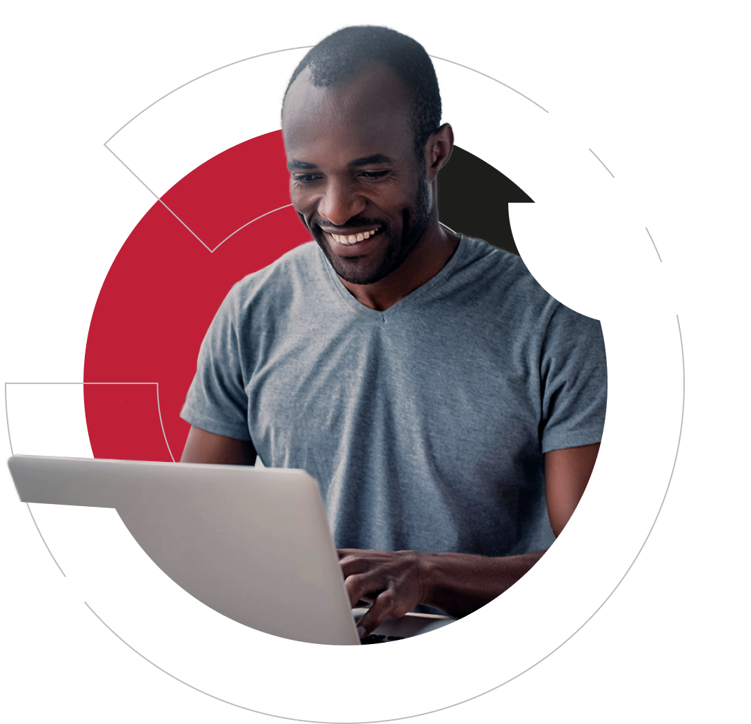 Afroamerican male sitting in front of a laptop and smiling towards the display.