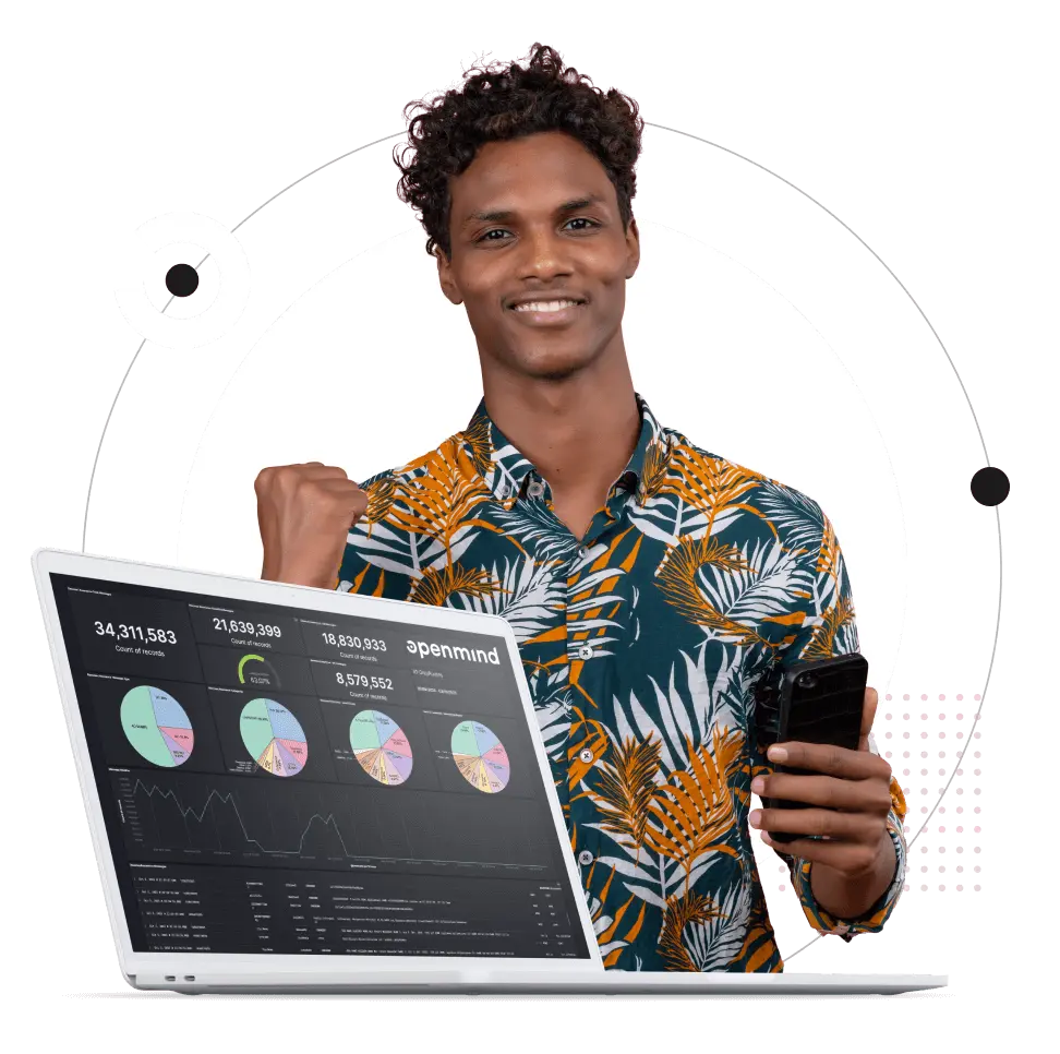 A male in winning pose holding a smartphone and rising a fist in success symbol. Openmind Network platform presented on a laptop device in fron of the person.